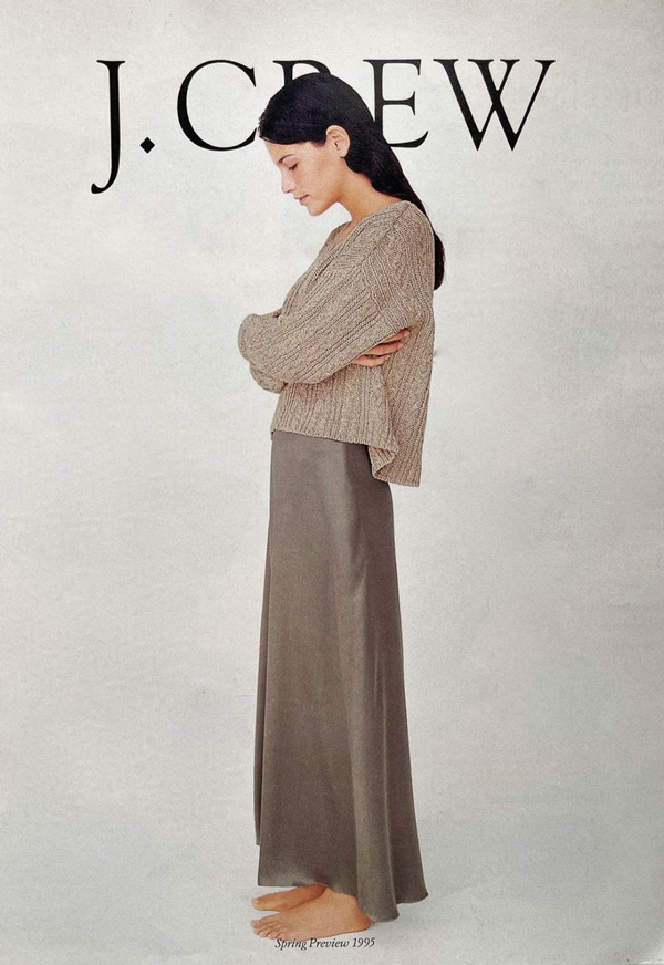 lady wearing beige sweater, silk gray skirt standing