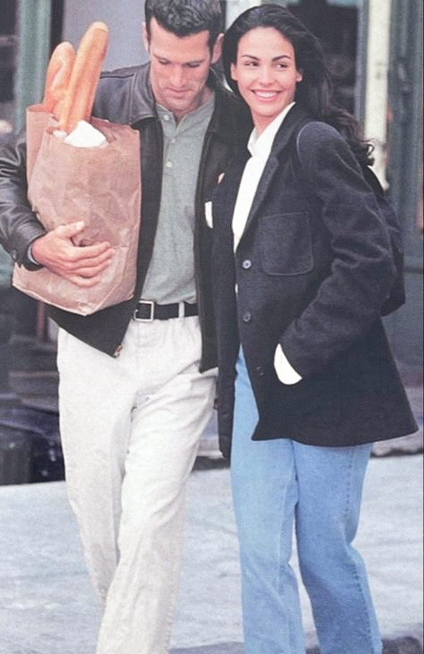 woman and man walking with groceries. lady wears black blazer and jeans, man wears olive green button up, chinos and leather jacket