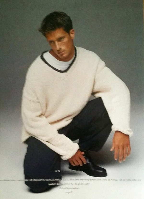 man crouching in white sweater, t shirt, black trousers, dress shoes